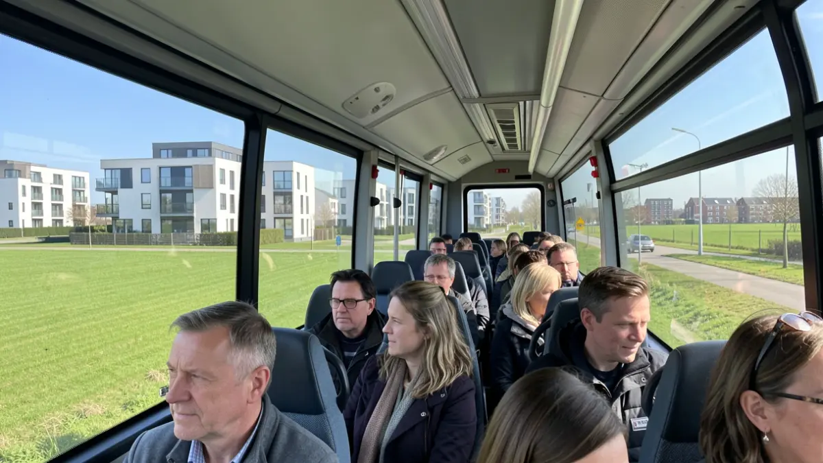 Groep mensen op een geleide busrit die naar sociale woningprojecten in Vlaanderen kijken.