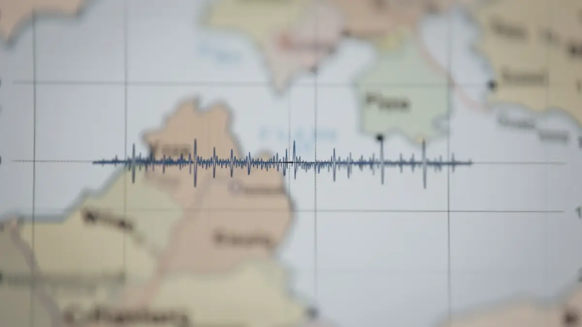 Generic image of a seismograph registering a slight tremor, with a blurred map of West Flanders in the background.
