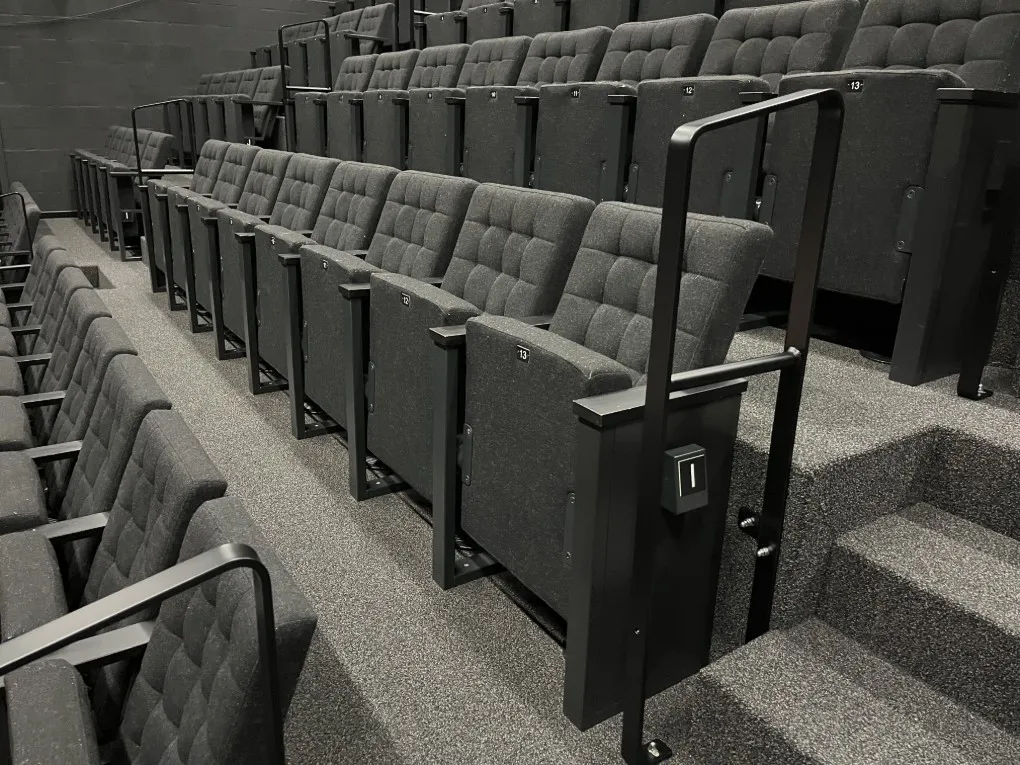 Lege rijen grijze klapstoelen in een theaterzaal. (vergroot foto)