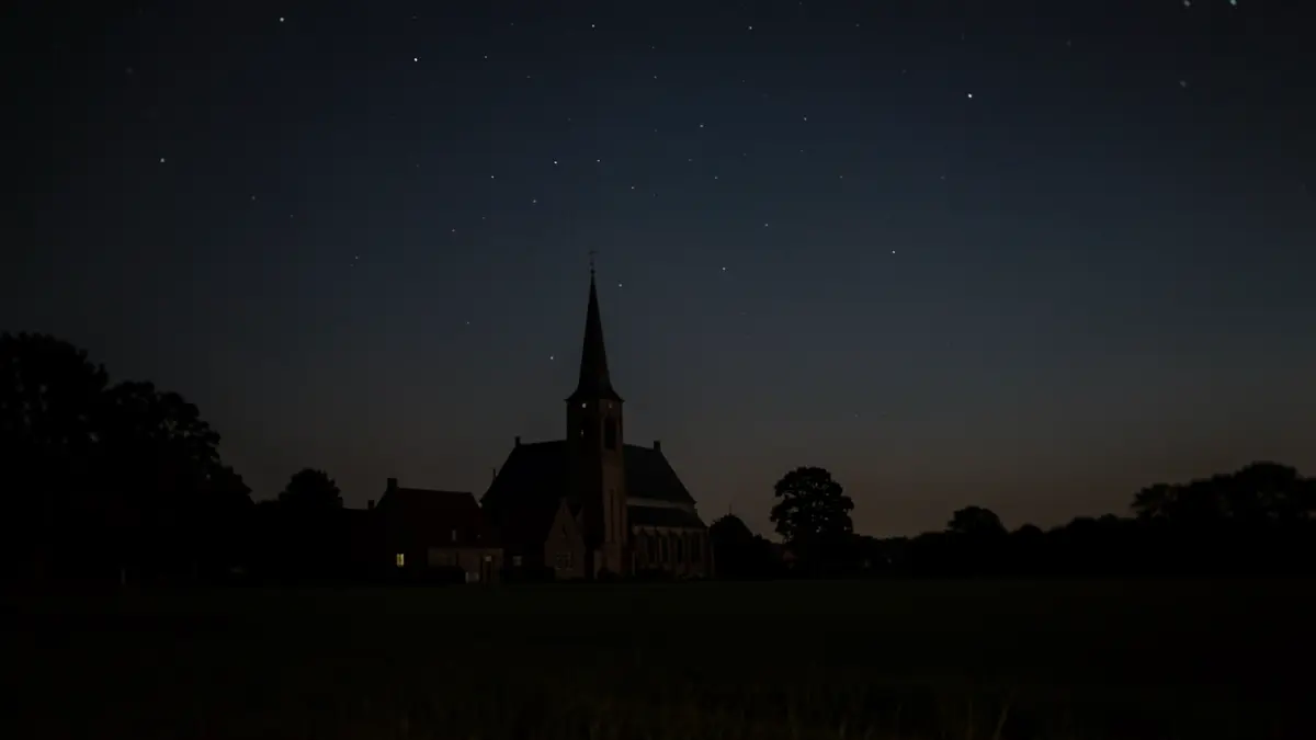 Generieke afbeelding van een donkere nachthemel met sterren boven een kerk in Vlaanderen.